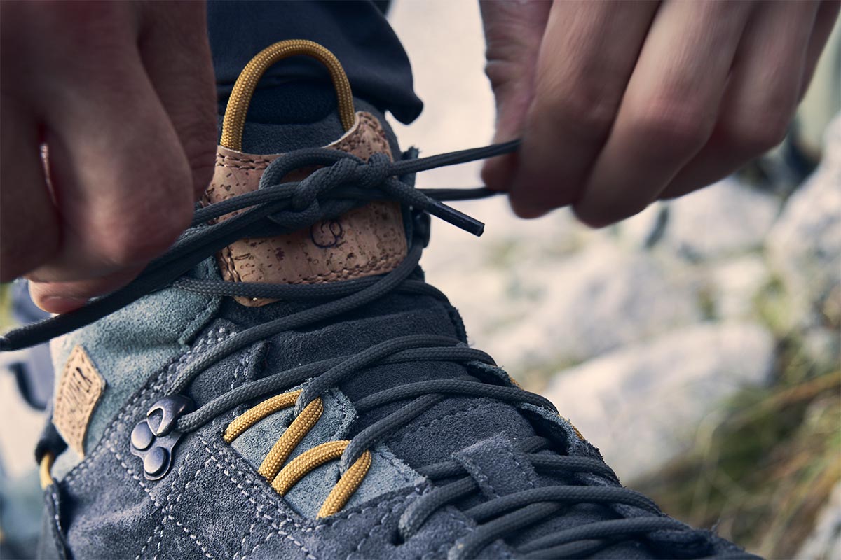 Blaue Bergschuhe werden an den Schnürsenkeln geschlossen