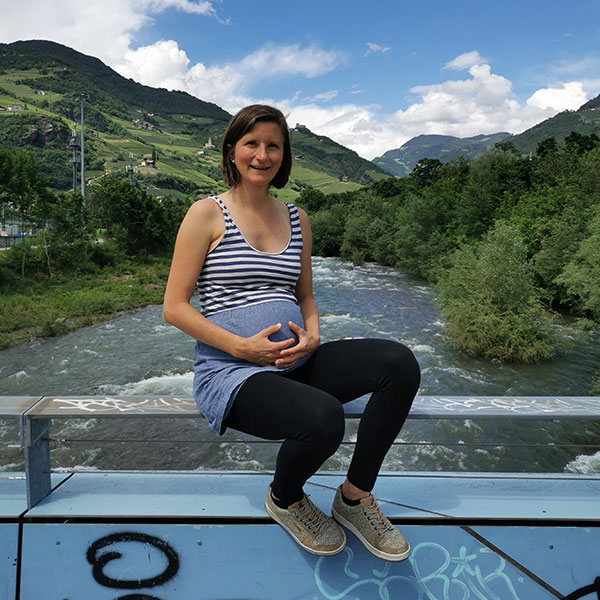 barfussschuhe-schwangerschaft-600-600-1 schwangere frau sitzt mit barfußschuhen auf einer brücke