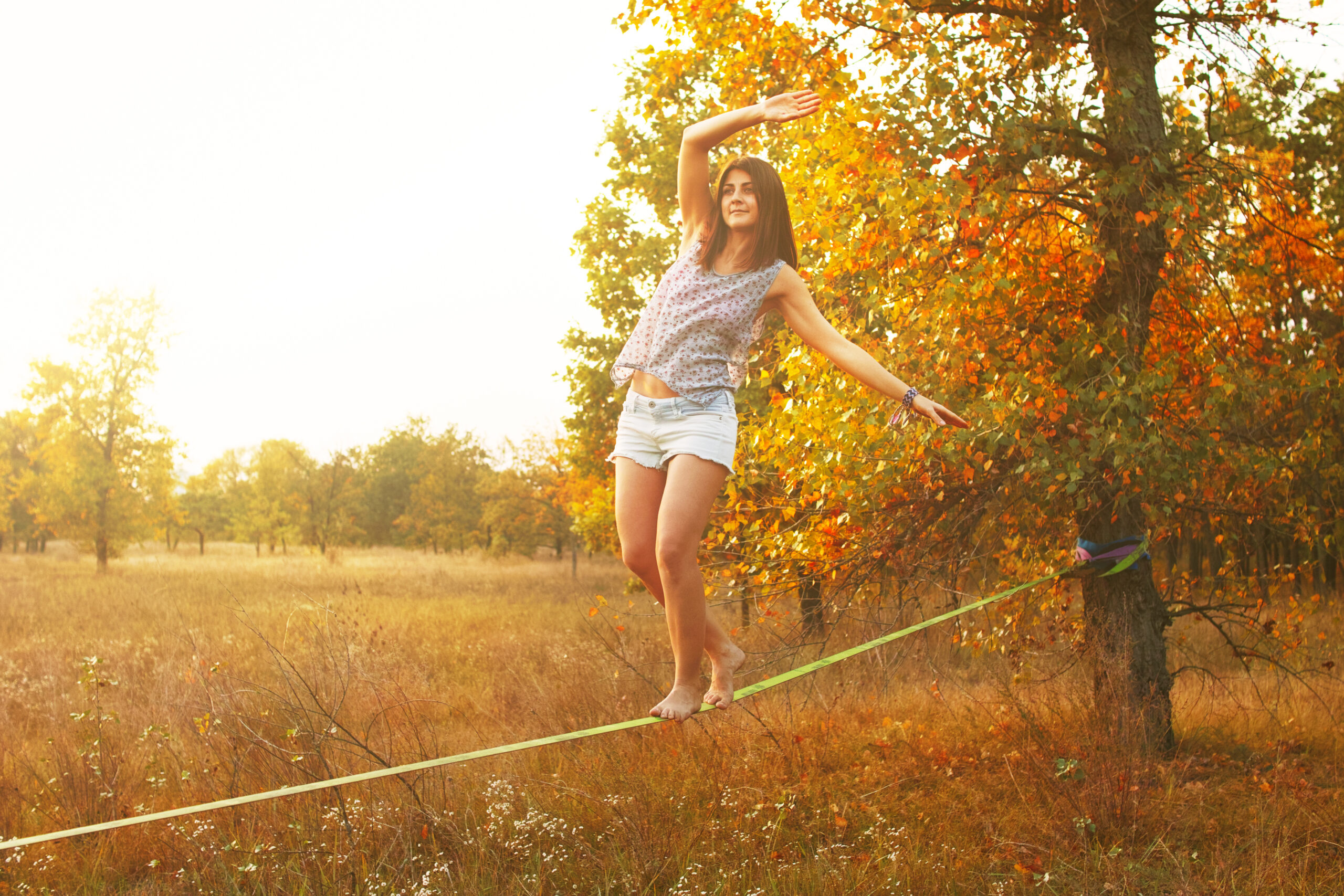 Mid Caucasian woman practicing slackline at sunset in the forest.