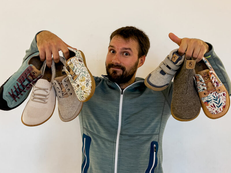 maximilian hält unterschiedliche barfußschuhe in händen