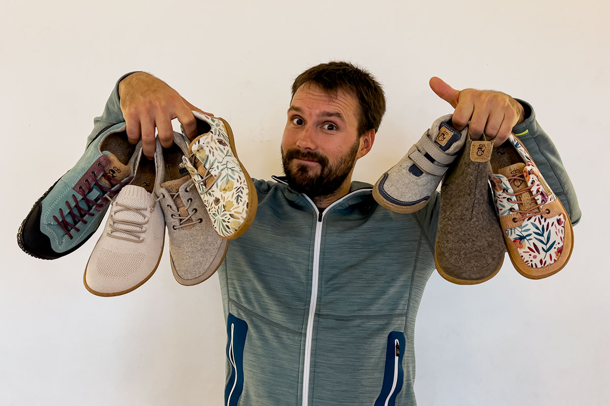 maximilian hält unterschiedliche barfußschuhe in händen