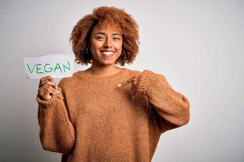 frau hält schild in der hand mit hinweis auf vegan barfußschuhe