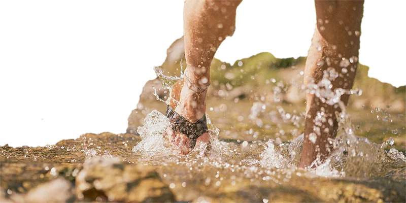 man mit sandalen aus kork läuft durchs wasser