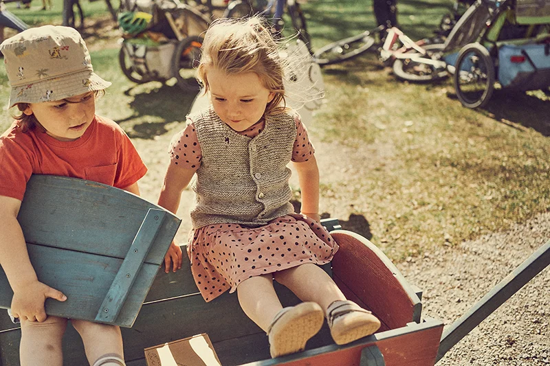 kinder sitzen mit barfußschuhen im bollerwagen