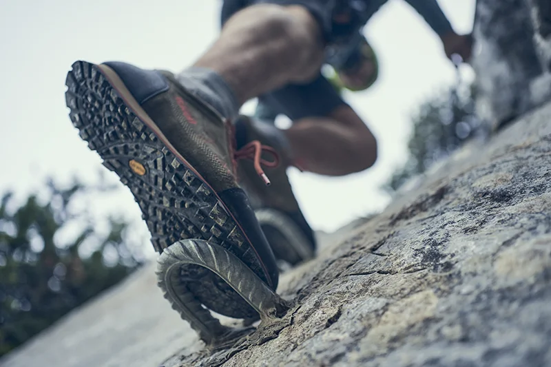 herr mit einem zustiegsschuhe am klettersteig