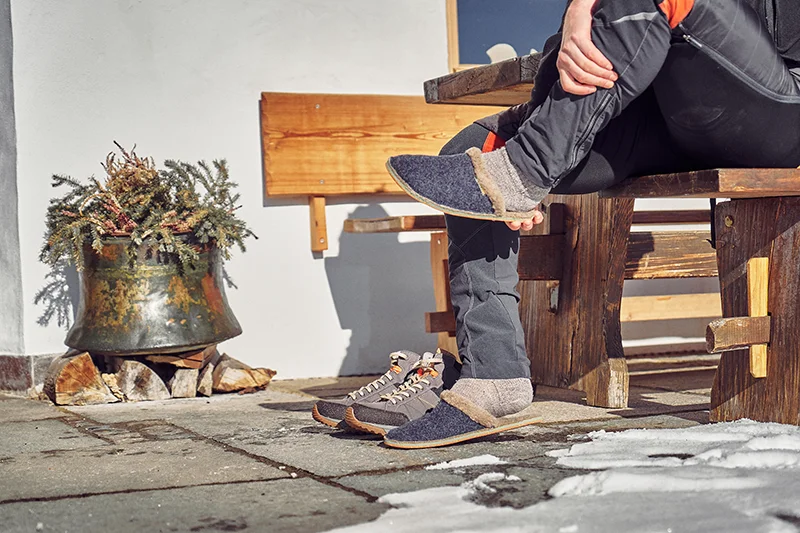 mann wechselt von bergschuen auf barfuß hausschuhe