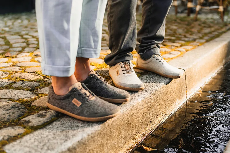 dame und herr stehen mit barfuß wollschuhen am wasser